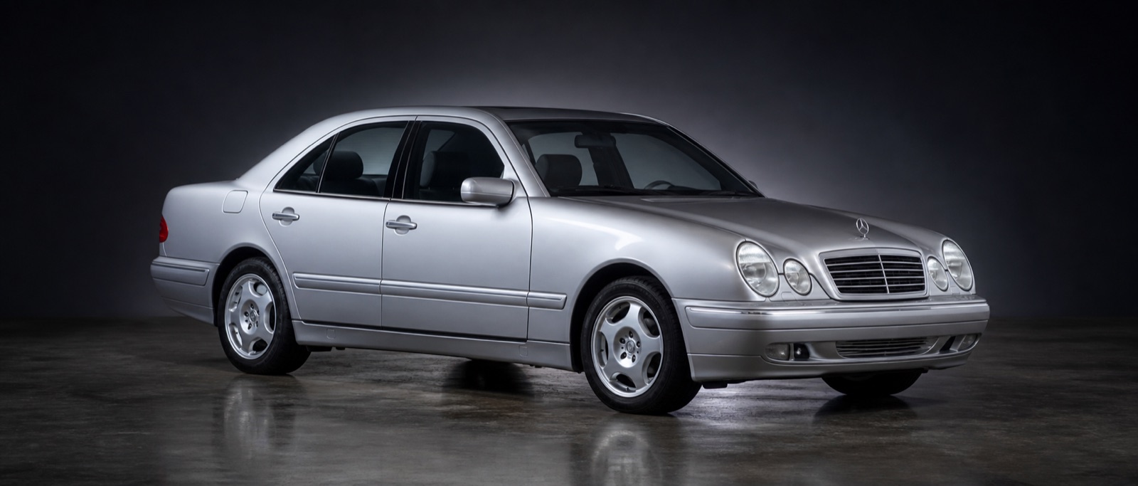 Silver Mercedes E430 in a dark photographic studio